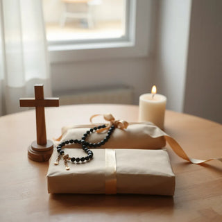 Meaningful Catholic keepsakes on a table including a cross, rosary, baptismal candle, and a gift box