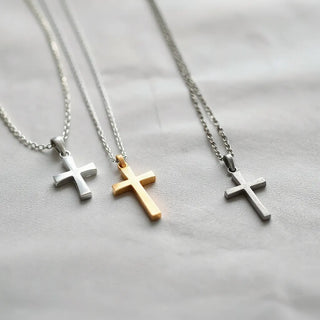Assorted cross necklaces with silver and gold pendants on a light fabric background