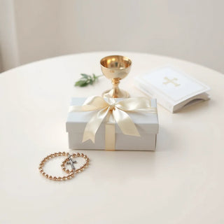 Gift box with communion-themed keepsakes, ribbon, rosary, and chalice centerpiece on a light table