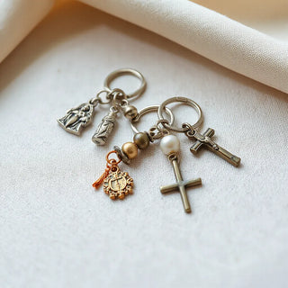 Assorted religious keychains with cross and rosary charms on a light fabric background