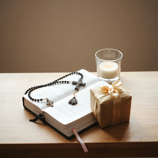 Catholic-themed gifts arranged with Bible, rosary, candle, and a wrapped box on a wooden table