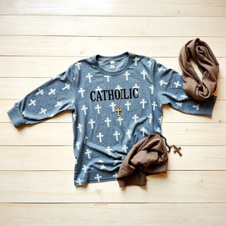 Modest Catholic-themed clothing and accessories arranged neatly on a wooden surface