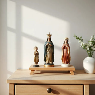 Small saint statues arranged on a wooden table in soft natural light