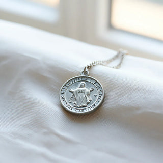 Silver Miraculous medal resting on neutral fabric with soft natural light
