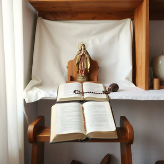Virgin Mary statue on a shelf beside an open devotional book and rosary