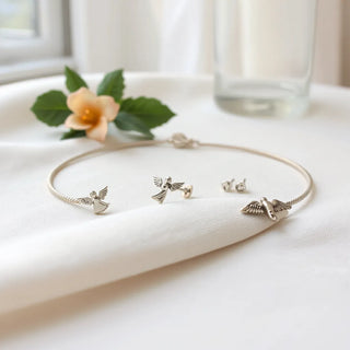 Sterling silver angel pendant necklace with delicate angel bracelet and earrings on soft fabric