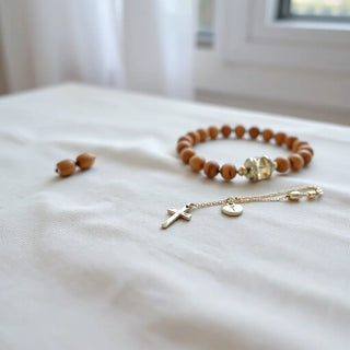 Delicate Catholic confirmation jewelry set with cross pendant and rosary-style chain on light fabric