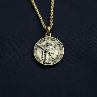 Saint Michael medal necklace resting on dark fabric with an angel and shield design clearly visible