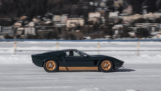A black sports car driving on a snowy road
