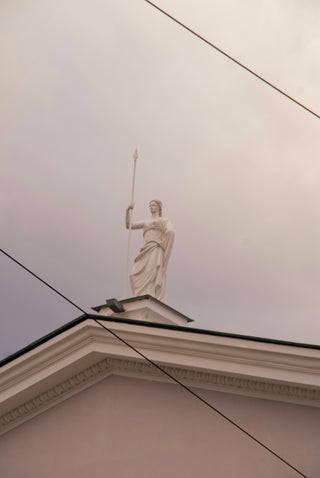 A statue stands on a building's roof.