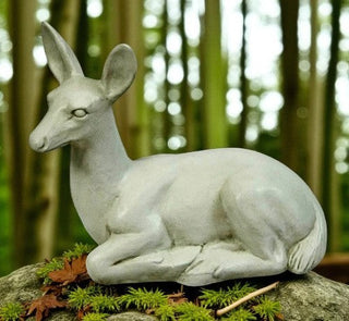 Statue of a fawn sitting with legs folded, head turned gently, for garden display — detail view